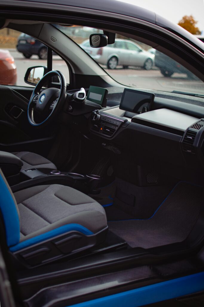 Luxurious BMW interior with black and blue seats, dashboard, and steering wheel in daylight.