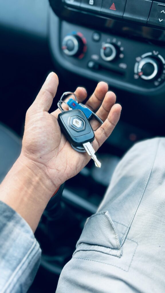 Hand holding car keys inside a vehicle, showing dashboard details.